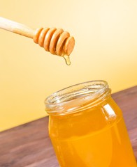 honey jar on wood table and golden background with wooden dipper