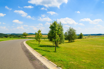 Road along farming field in summer on sunny day, Poland