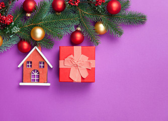 Toy house and pine branches with gift on blue background.