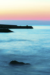 Sunrise on beach with rocks and sea
