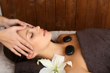 Obraz na płótnie Canvas Beautiful young woman in spa salon with spa stones taking head