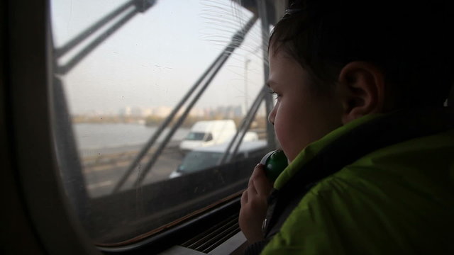 boy looking out the window at the cars in the metro 2