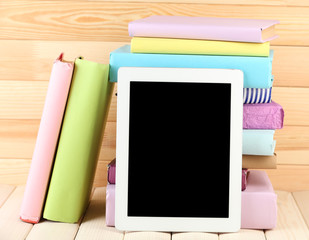 PC tablet and books on wooden table, on wooden background