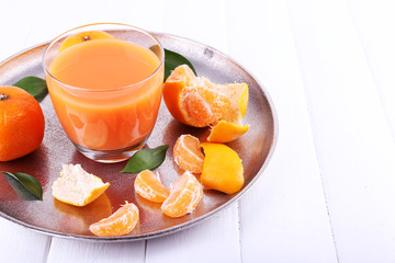 Glass of juice and ripe sweet tangerine on wooden table