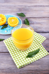 Fototapeta premium Glass of juice and ripe sweet tangerine on wooden table
