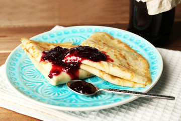 Plate of delicious pancakes with berry jam on wooden background