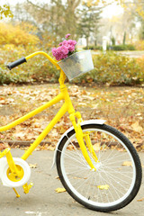 Beautiful yellow bicycle in autumn park with bouquet of