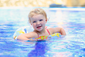 Happy little girl relaxing in the pool with inflatable ring