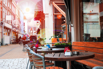 Urban street with a picturesque cafe in rays sun