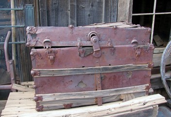 Old pink steamer trunk displayed on the side of a barn