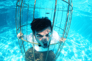 Funny groom underwater in a bird cage