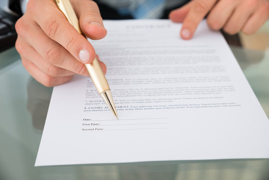 Businessman With Pen And Contract Document At Desk