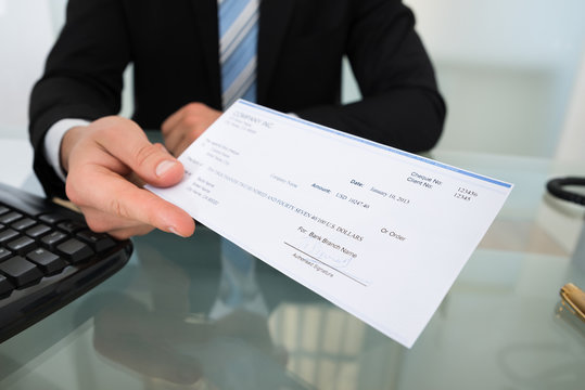 Midsection Of Businessman Giving Cheque