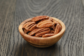 pecan nuts in olive wood bowl on oak table