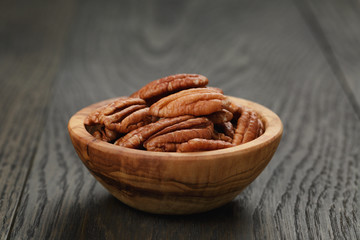pecan nuts in olive wood bowl on oak table
