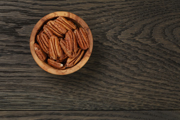 pecan nuts in olive wood bowl on oak table
