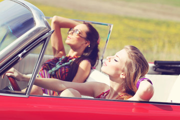 Beautiful ladies with sun glasses riding a vintage retro car