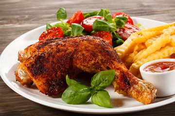 Grilled chicken legs with chips and vegetables