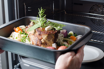 Frau schiebt Braten in den Ofen