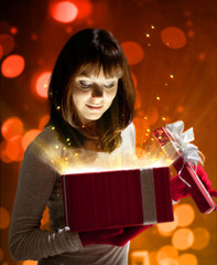 Young woman keeps Christmas red gift with magic light.