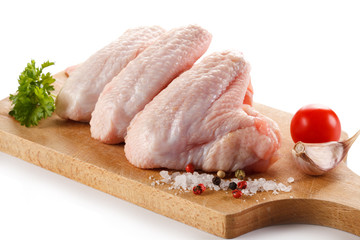 Raw chicken wings on cutting board on white background