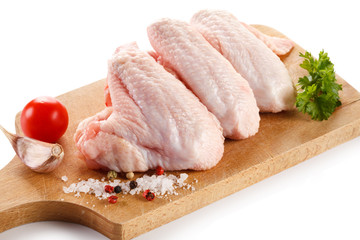 Raw chicken wings on cutting board on white background