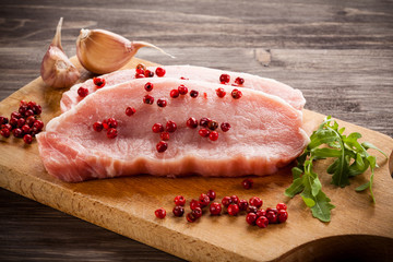 Raw pork chops on cutting board and vegetables