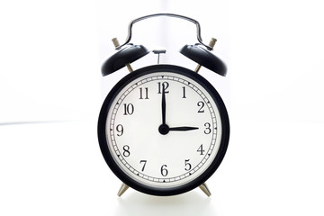 Oldfashioned black glossy alarm clock showing 3 o'clock