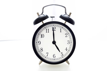 Oldfashioned black glossy alarm clock showing 5 o'clock