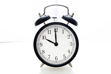 Oldfashioned black glossy alarm clock showing 10 o'clock