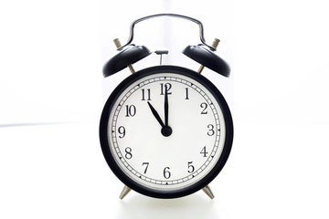 Oldfashioned black glossy alarm clock showing 11 o'clock