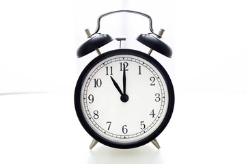 Oldfashioned black glossy alarm clock showing 11 o'clock