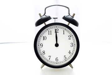 Oldfashioned black glossy alarm clock showing 12 o'clock