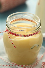 Custard cream in glass jar on blue wooden background
