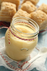 Custard cream in glass jar on blue wooden background