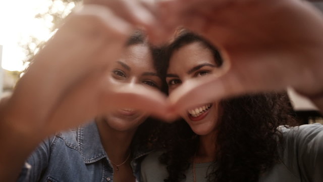 Best mixed race girl friends show heart shape to camera with han
