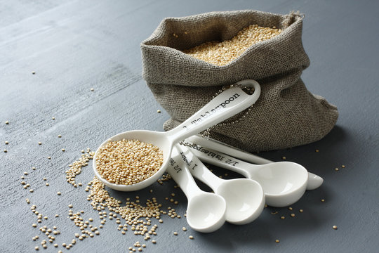 Quinoa grain in small burlap sack and porcelain measuring spoons