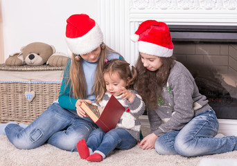 Elder sisters reading a Christmas story his little sister.