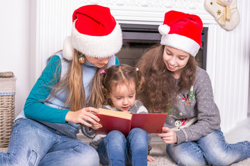 Elder sisters reading a Christmas story his little sister.