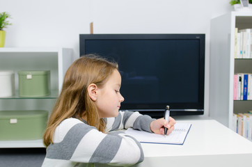 kind macht hausaufgaben vor dem fernseher