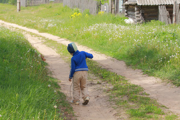 Kid walking alone outdoors by rural road