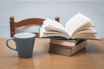 Some books and a cup of milk or coffe on a table