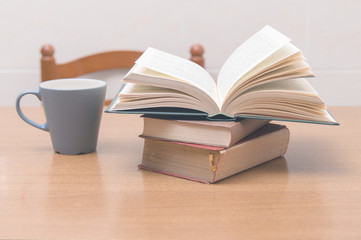 Some books and a cup of milk or coffe on a table