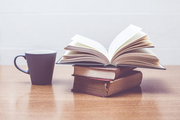 Some books and a cup of milk or coffe on a table