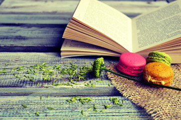 Macaroons with open book on a wooden background