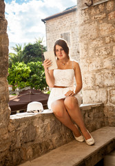 young woman using digital tablet on street of old city