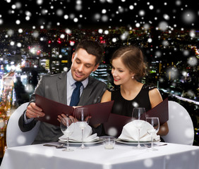 smiling couple with menus at restaurant
