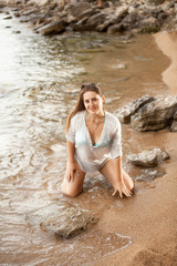 sexy woman in shirt kneeling on sandy beach