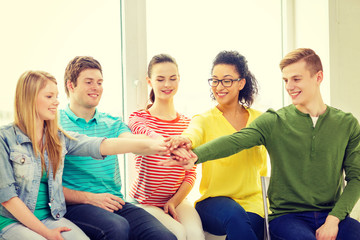 smiling students with hands on top of each other