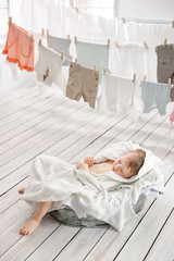 Fototapeta na wymiar Sleeping little child into the bowl with clothes in the laundry